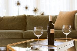 bottle of wine with empty wine glasses on table next to couch in living room